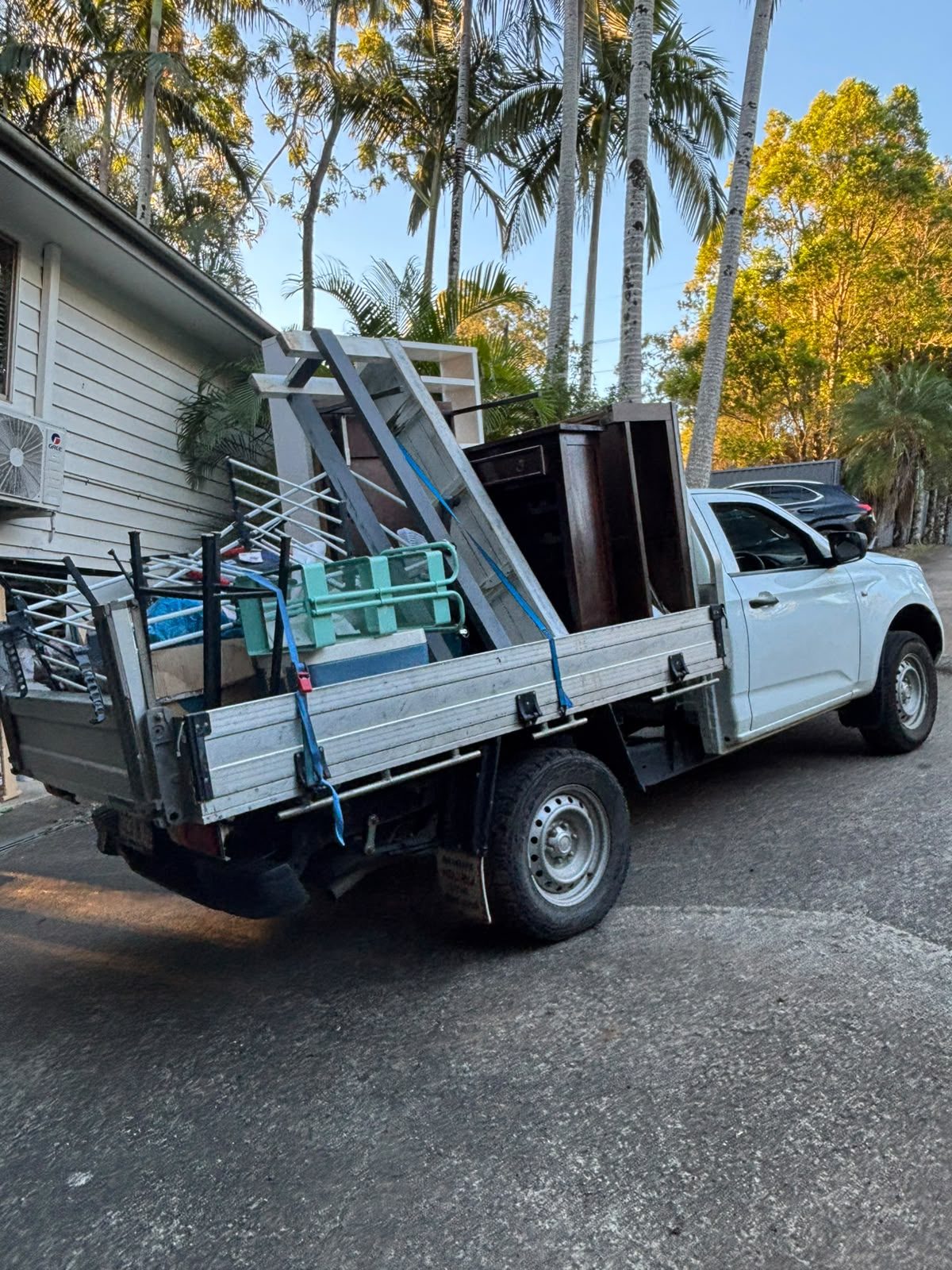 Ute loaded with bikes, shelving and furniture strapped down for a rubbish run
